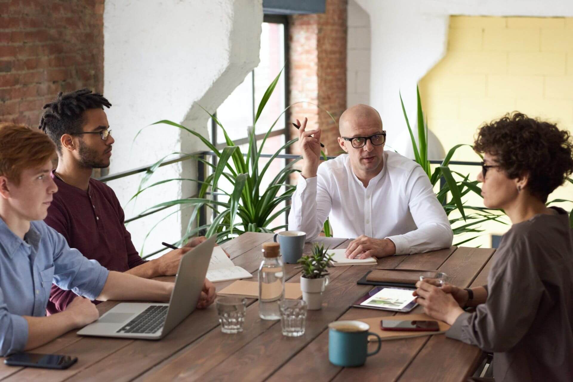 man sitting at the head of table talking to coworkers around the table