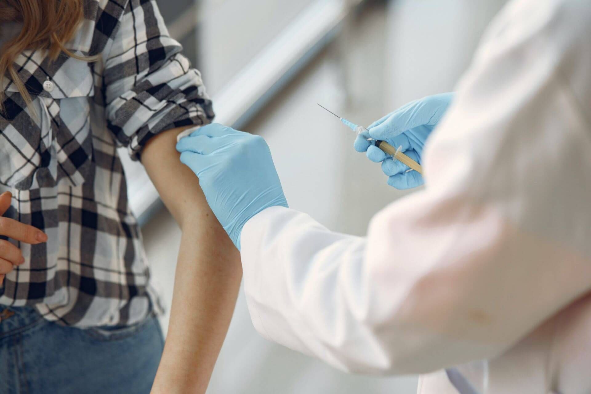 doctor holding a syringe while cleaning a woman arm