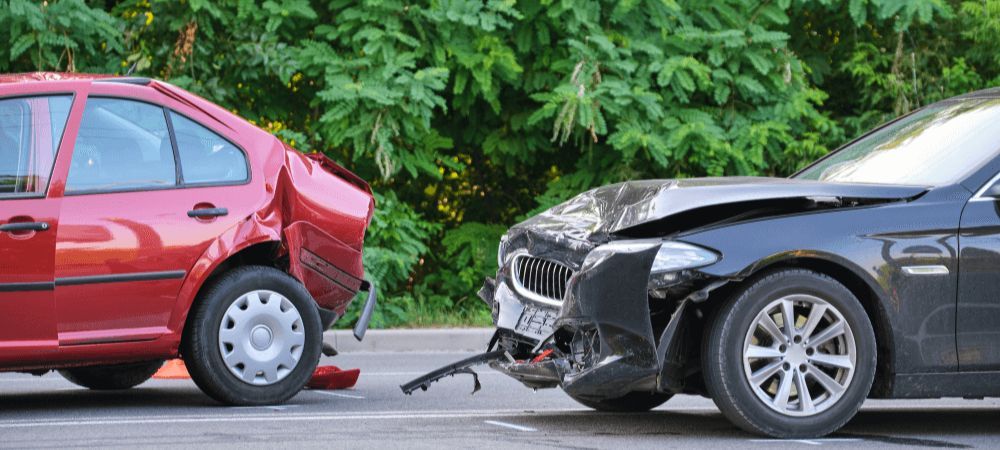 accident between red and black car with damage to front and rear of vehicles on roadway