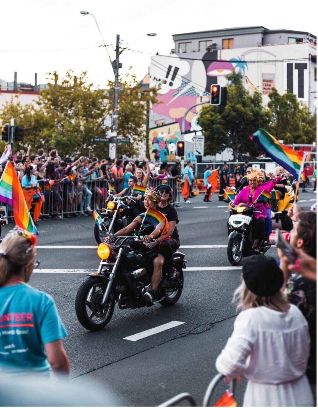 motorcycles driving down the road with rainbow flags