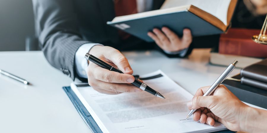 Lawyer sitting down at a desk pointing towards a document