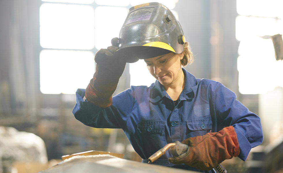 female welder lifting her welders helmet to look down